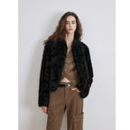 Person wearing a black fur jacket and brown pants against a white background