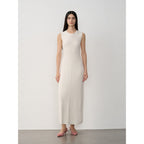 Woman wearing a white sleeveless dress against a plain background