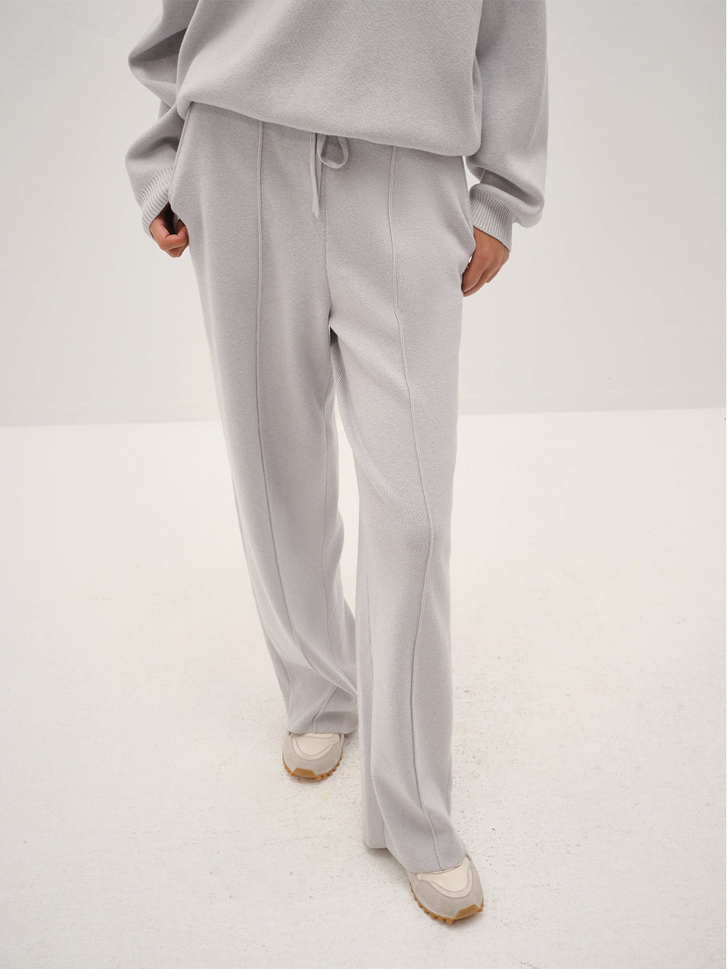Person wearing a gray outfit with wide-leg pants on a white background