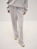 Person wearing a gray outfit with wide-leg pants on a white background