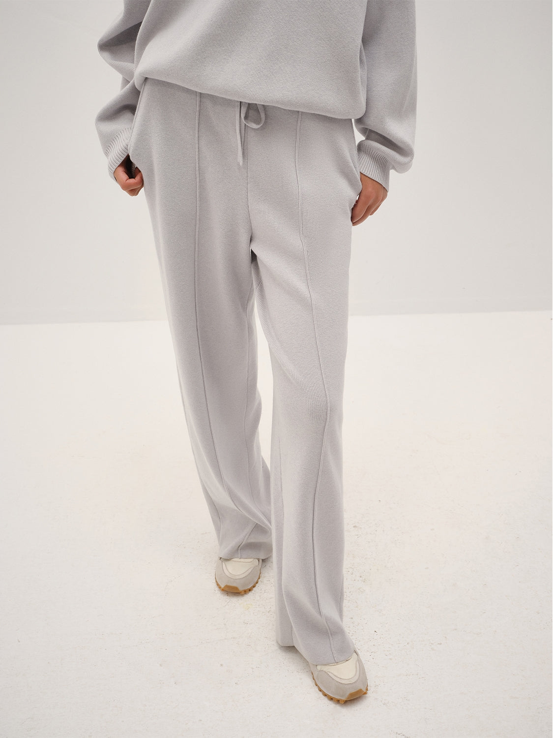 Person wearing a gray outfit with wide-leg pants on a white background