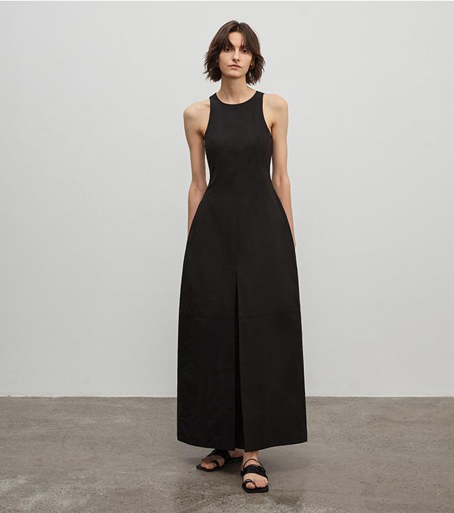 Woman wearing a black sleeveless dress against a plain background