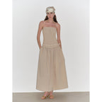 Woman wearing a beige strapless dress with a white headband on a white background