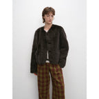 Person wearing a dark brown fuzzy jacket and plaid pants against a white background