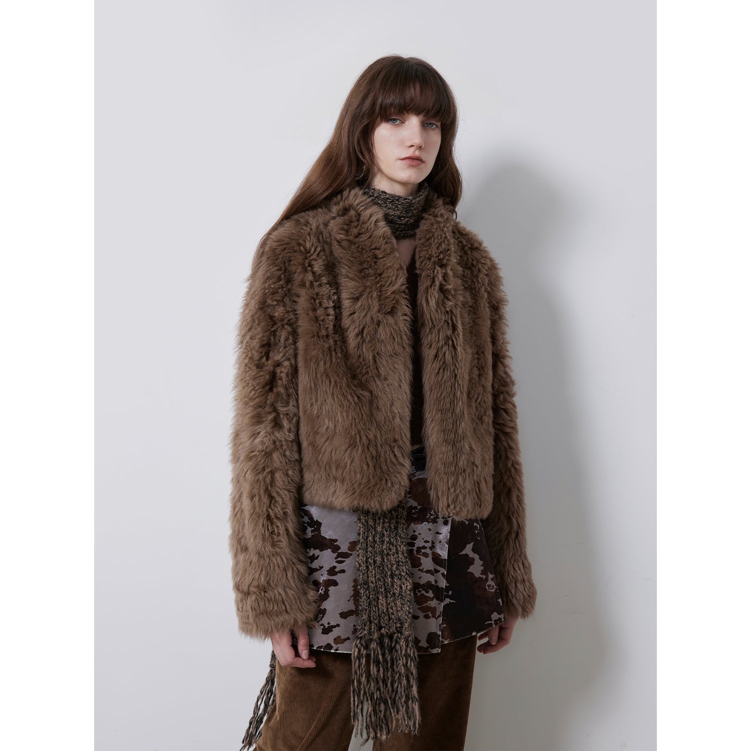 Woman wearing a brown fur coat with a plain background