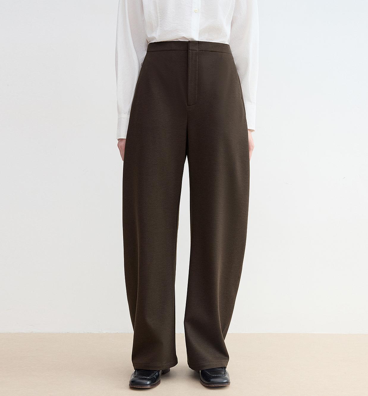 Person wearing brown wide-leg pants with a plain background