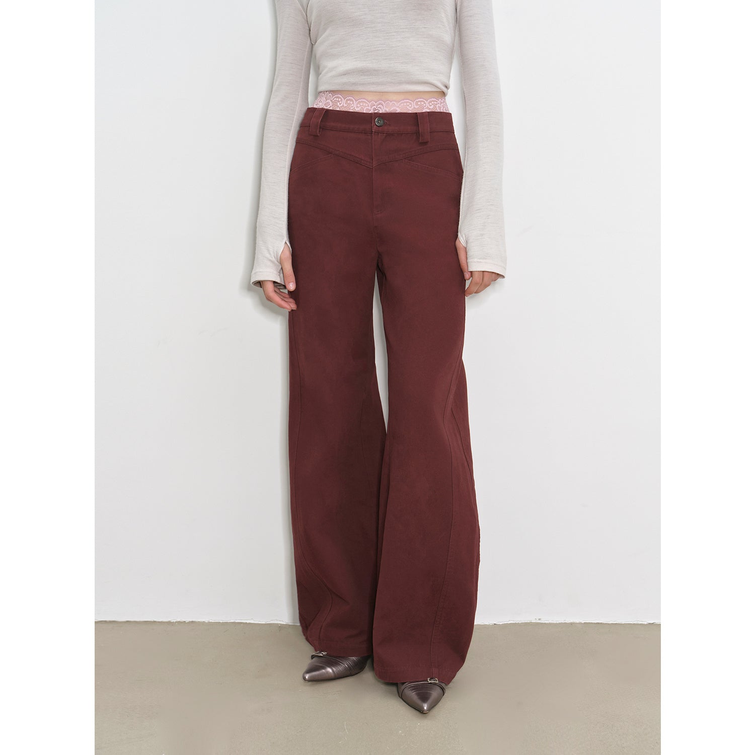 Person wearing maroon flared pants with a plain white background