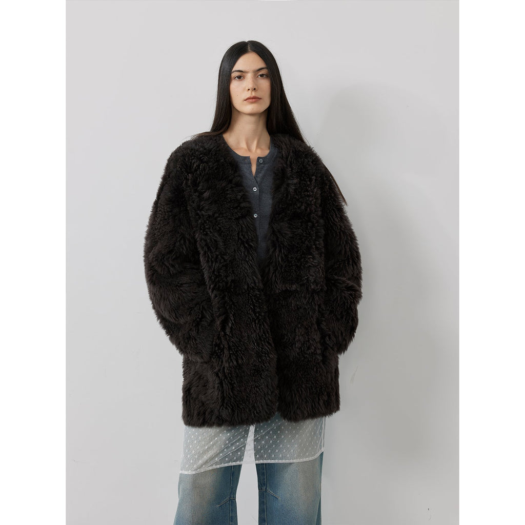 Person wearing a black fluffy coat against a plain background