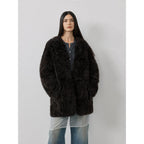 Person wearing a black fluffy coat against a plain background