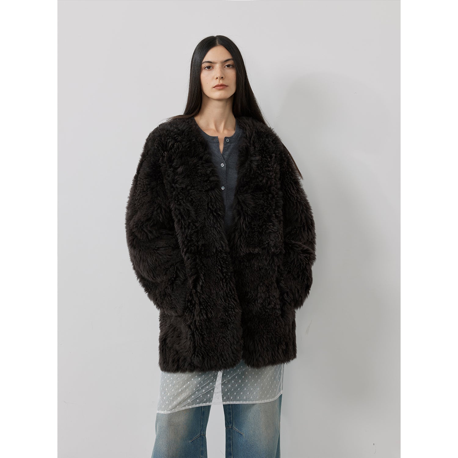 Person wearing a black fluffy coat against a plain background