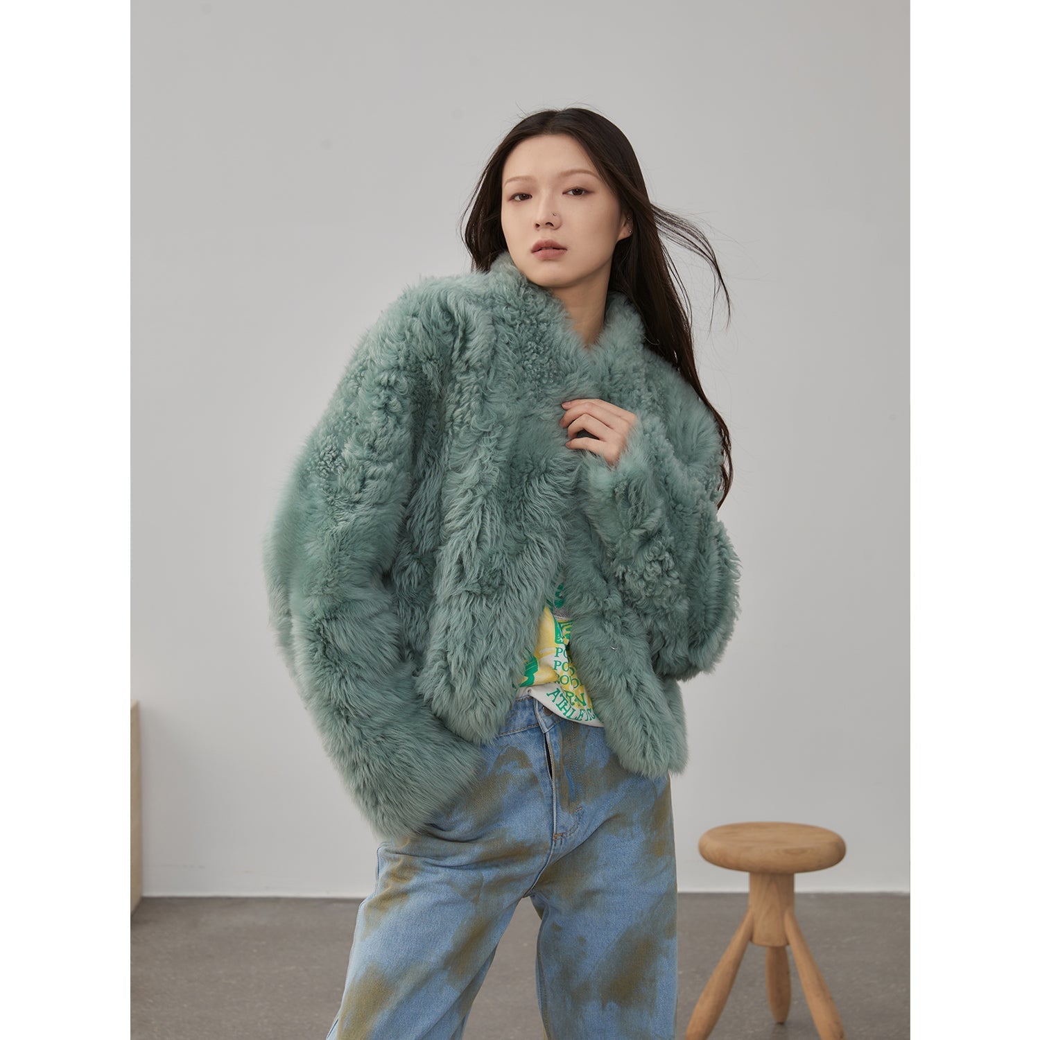 Person wearing a fluffy green sweater with a neutral background