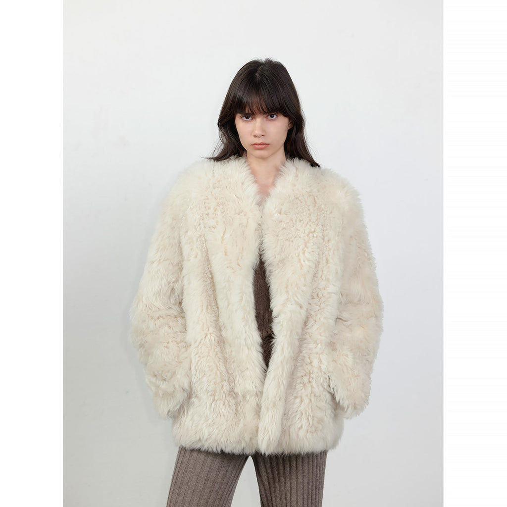 Person wearing a fluffy white coat against a plain background