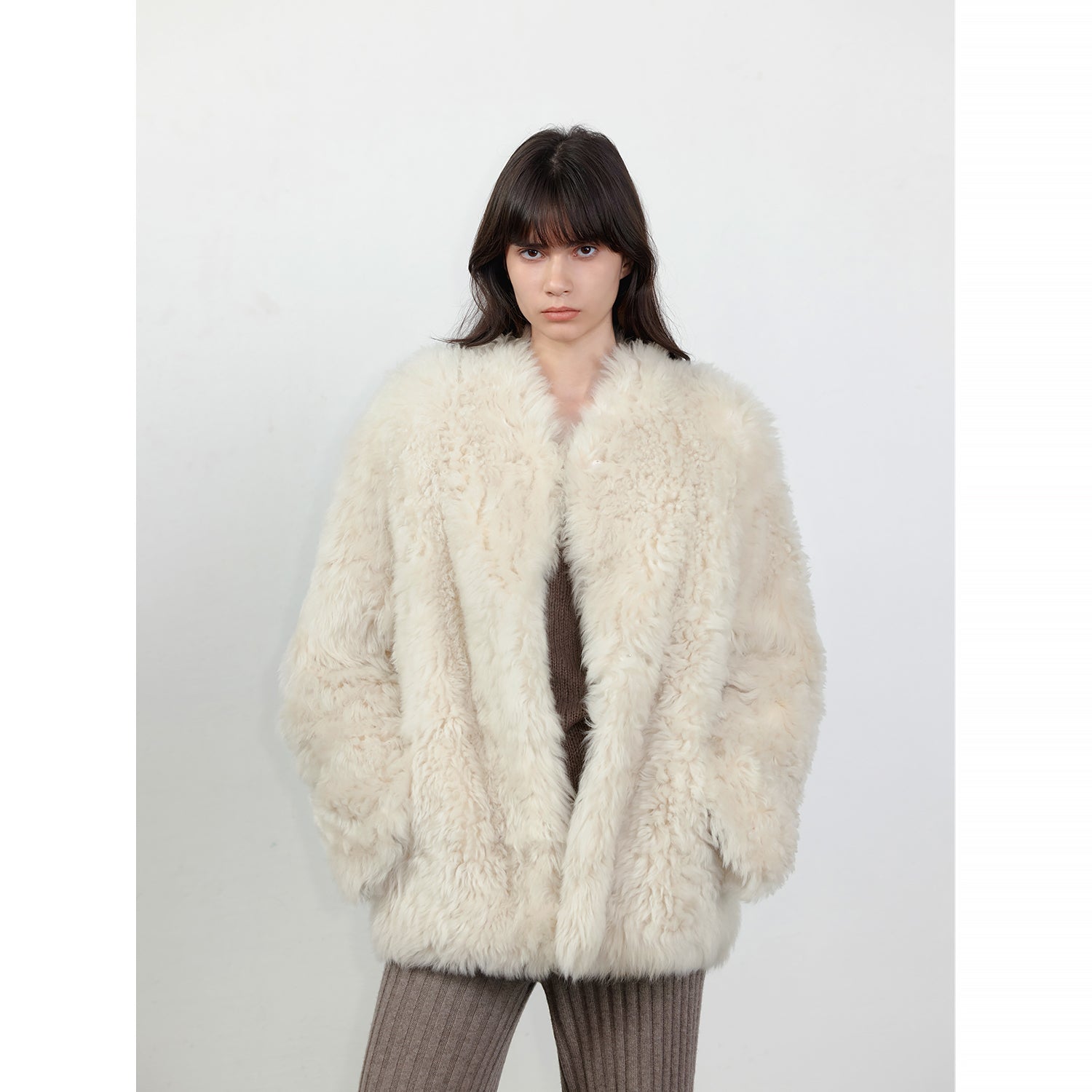 Person wearing a fluffy white coat against a plain background