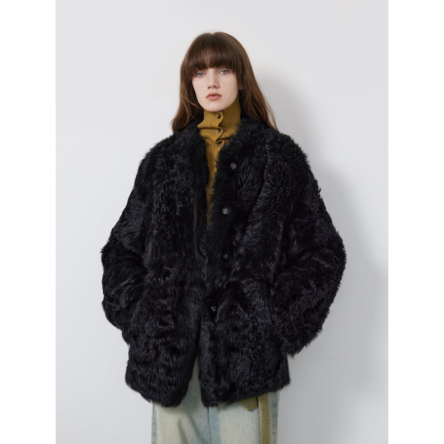 Person wearing a black fluffy coat against a white background
