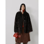 Woman wearing a black fur coat with a red handbag on a white background