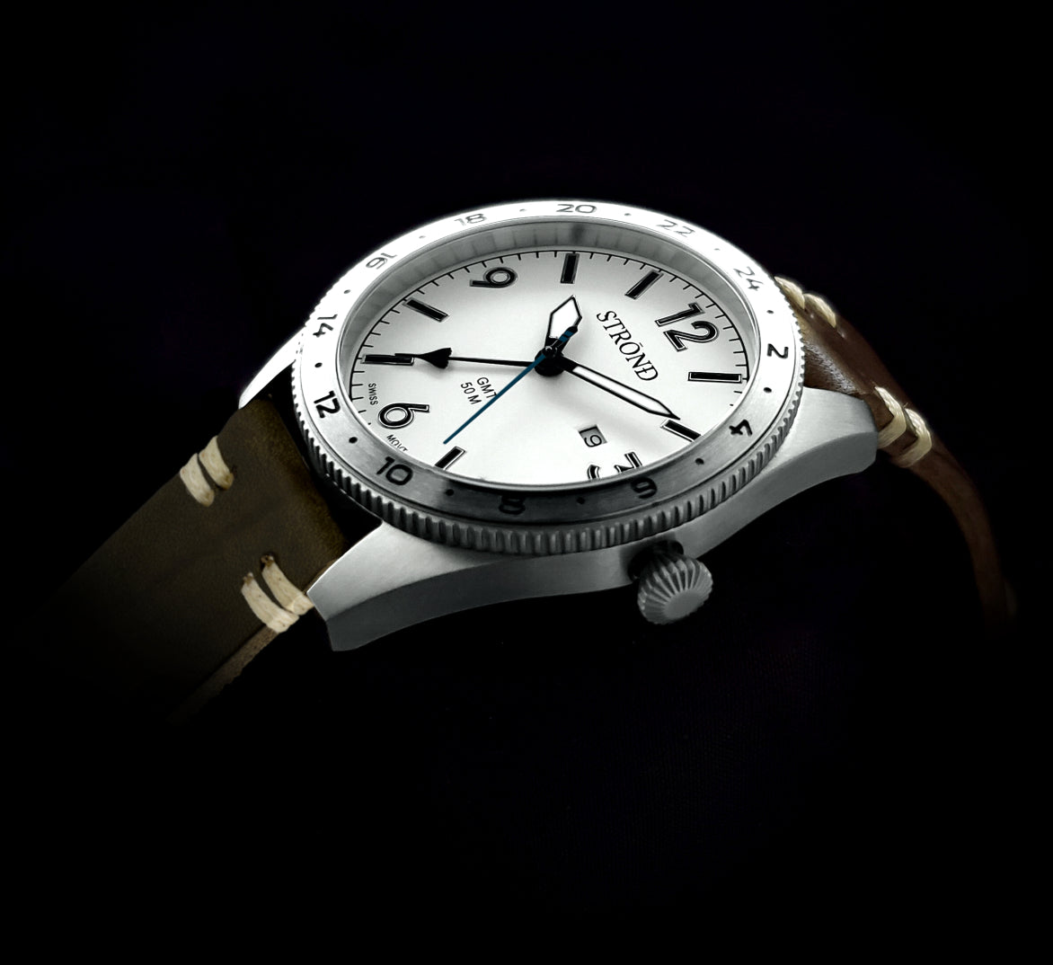 Watch with brown strap and silver case on a black background