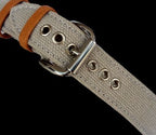 Close-up of a beige leather belt with metal buckle on a black background
