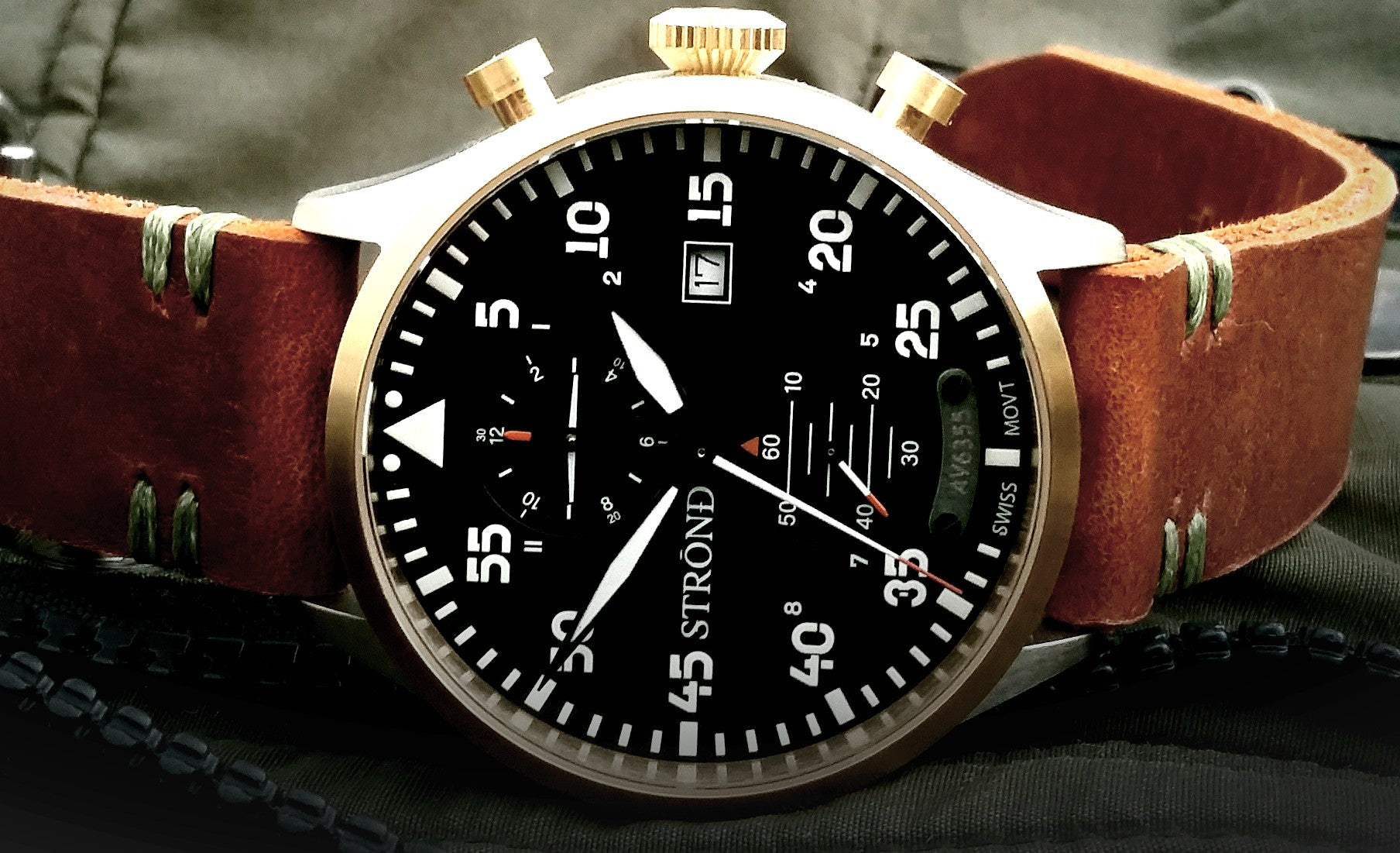 Strand watch with brown leather strap and black dial on a dark background