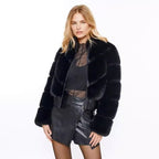 Woman wearing a black fur coat and black outfit on a white background