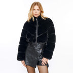 Woman wearing a black fur jacket and leather skirt on a white background