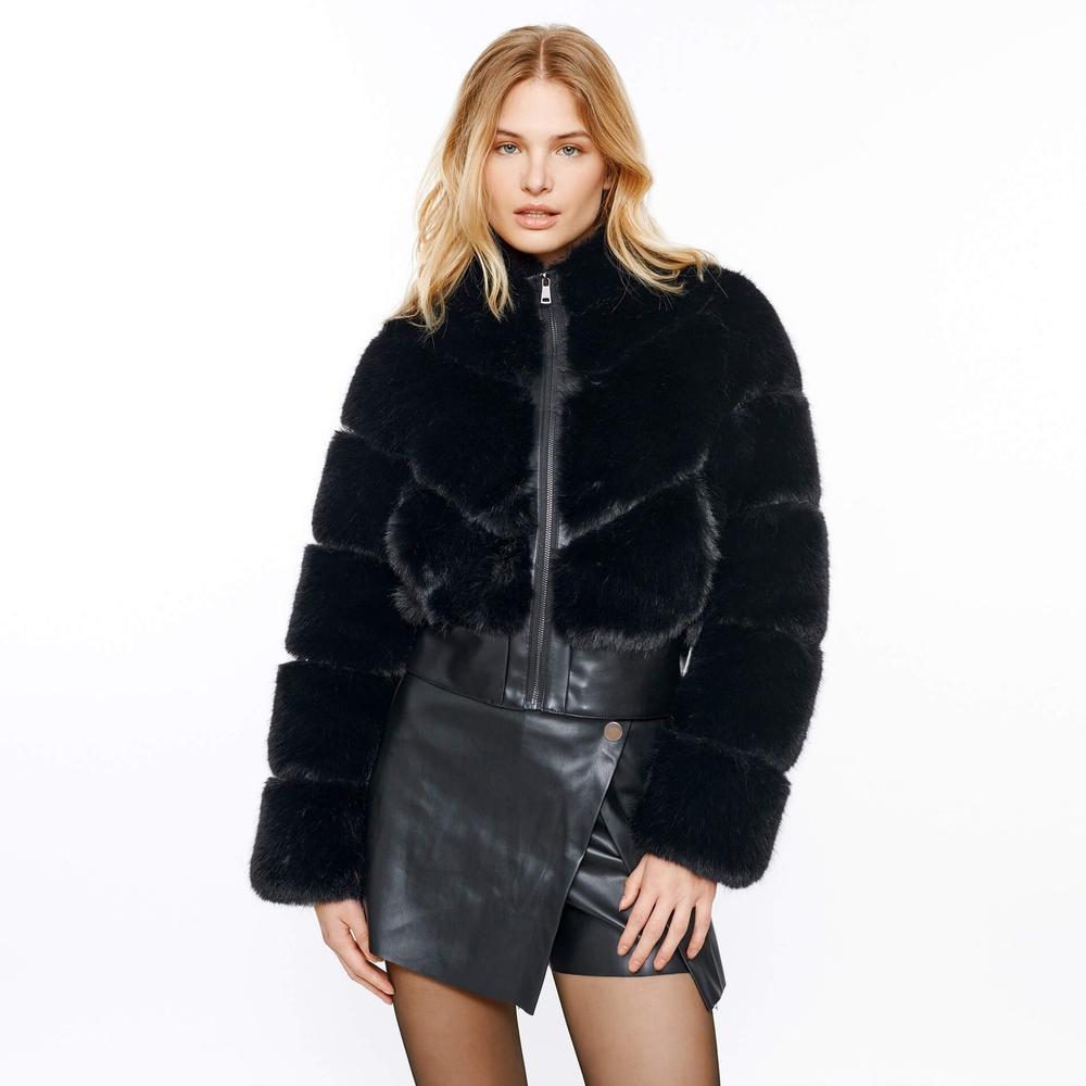 Woman wearing a black fur jacket and leather skirt on a white background