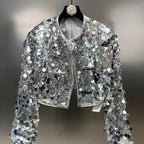 Silver sequin jacket on a hanger against a neutral background