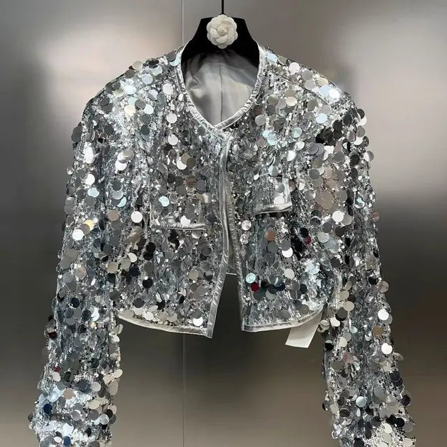 Silver sequin jacket on a hanger against a neutral background