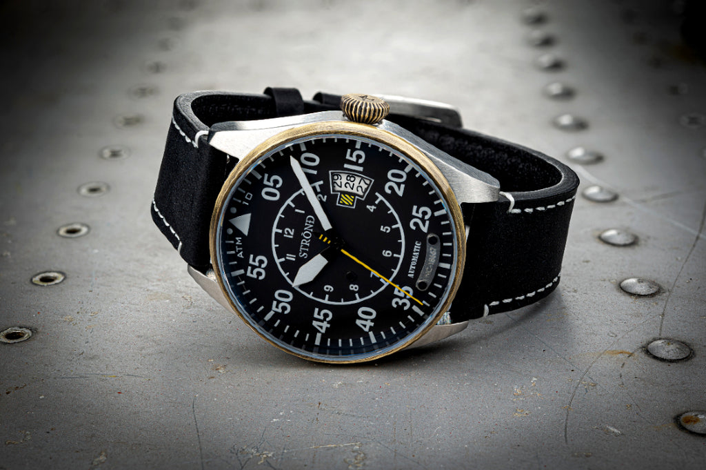 Wristwatch with black strap and detailed face on a metallic surface