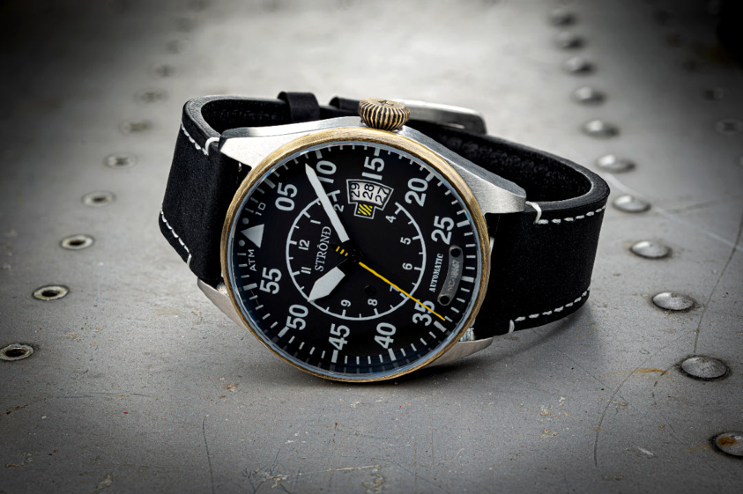 Wristwatch with black strap and detailed face on a metallic surface