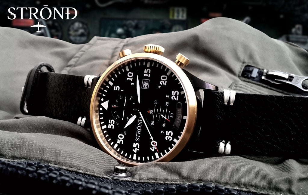 Strond watch with black strap and gold case on a textured surface