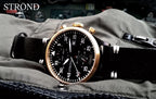 Strond watch with black strap and gold case on a textured surface