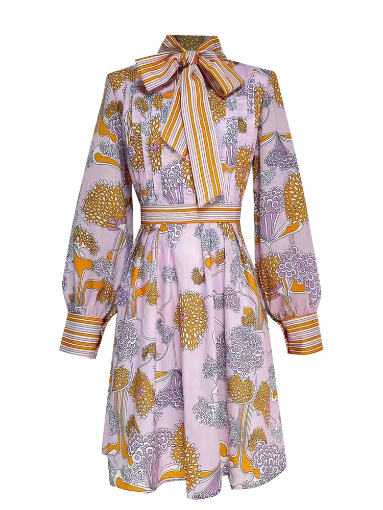Patterned dress with long sleeves and a tie neckline on a white background
