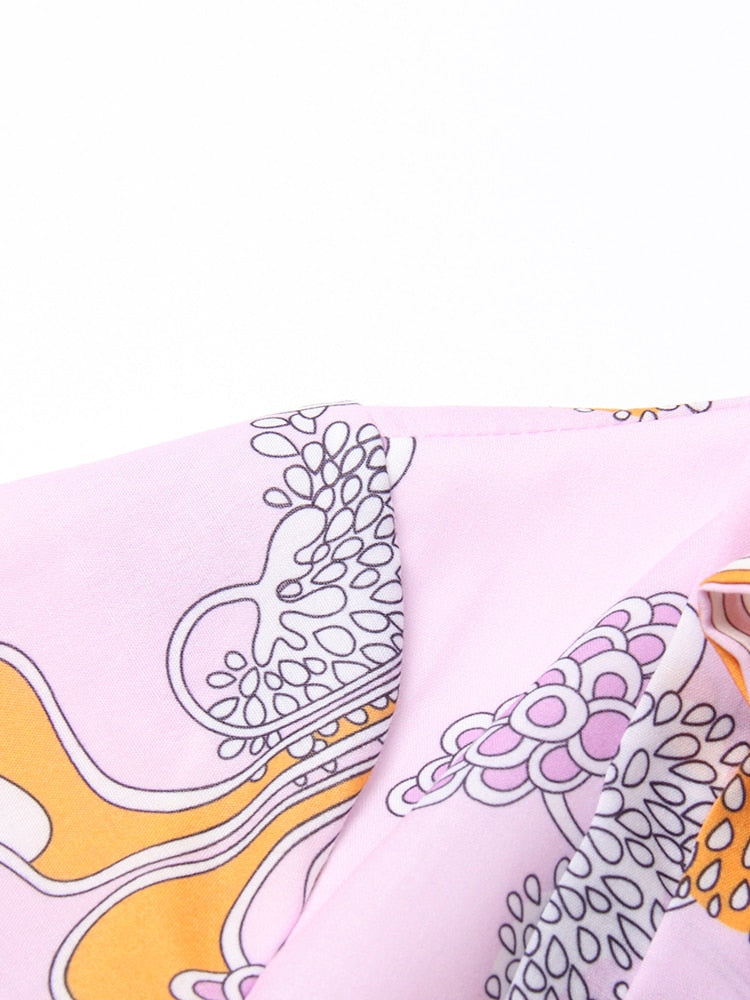 Close-up of a pink fabric with abstract floral patterns in black and yellow.