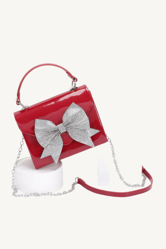 "Enamel clutch with rhinestone ribbon and top handle – elegant, eye-catching evening bag with luxurious detailing."