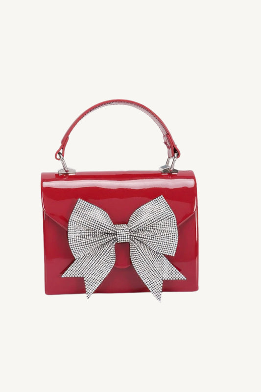 "Enamel clutch with rhinestone ribbon and top handle – elegant, eye-catching evening bag with luxurious detailing."
