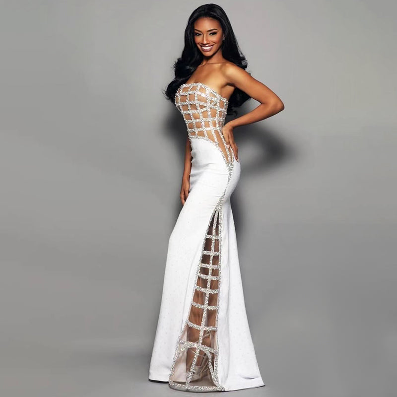 Woman wearing a white evening gown with sheer details on a gray background