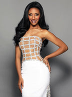 Woman wearing a strapless, beaded evening gown against a gray background
