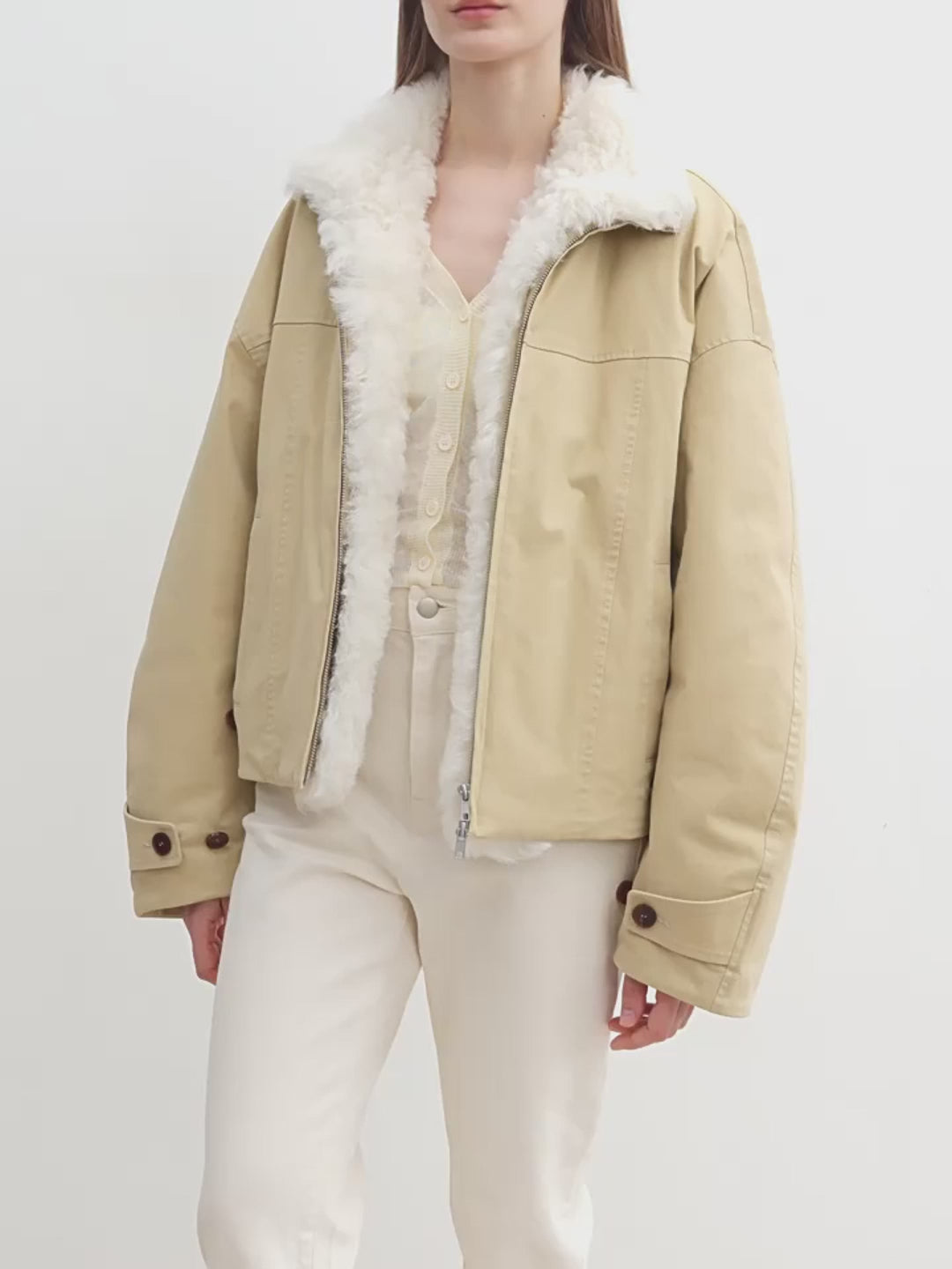 Beige jacket with white fur lining worn by a person on a white background