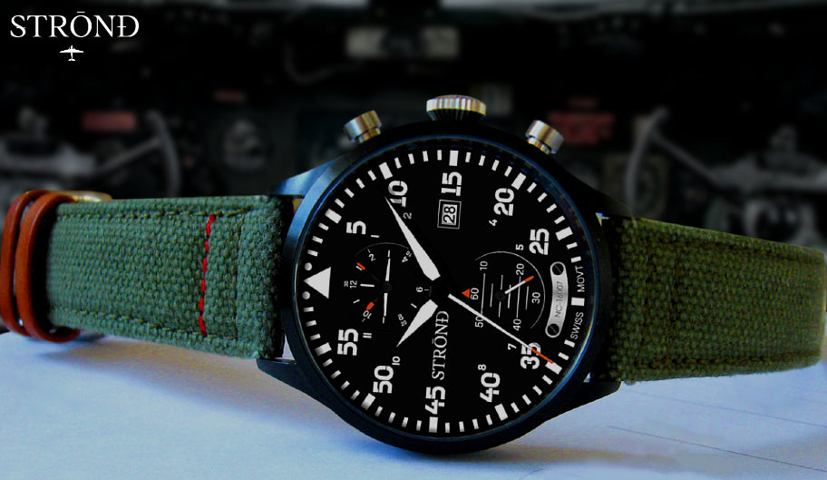 Green wristwatch with detailed face and brown strap on a blurred background
