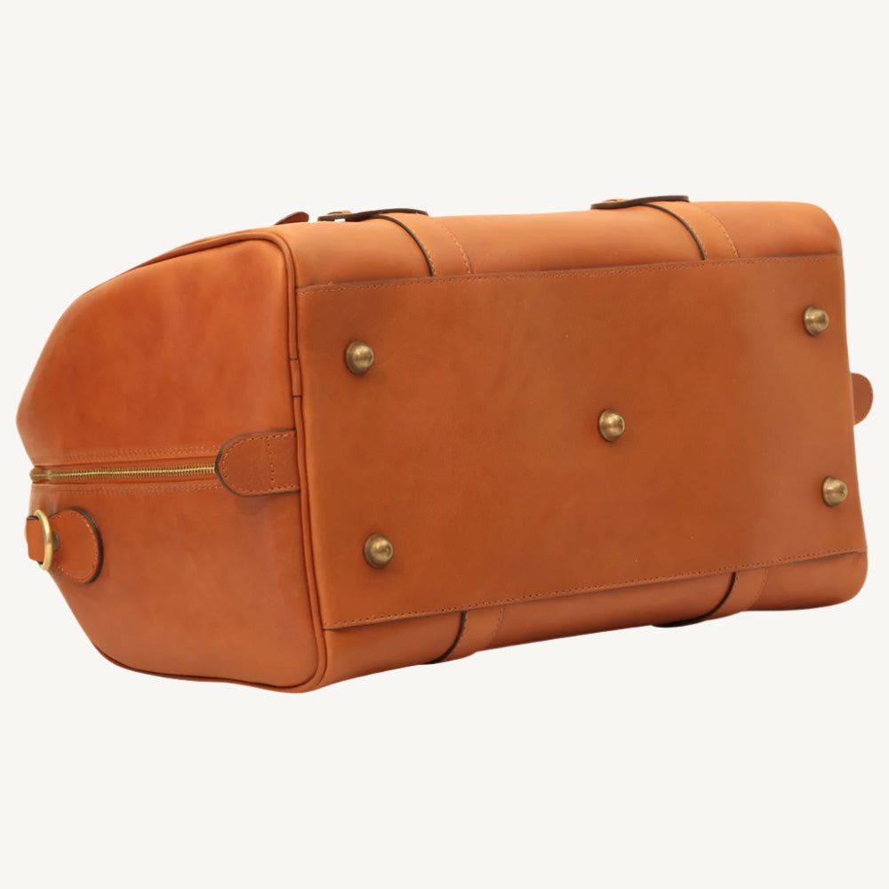 "Full-grain calfskin leather travel bag with synthetic lining, interior zip pocket, and padded adjustable strap – stylish and durable for travel"