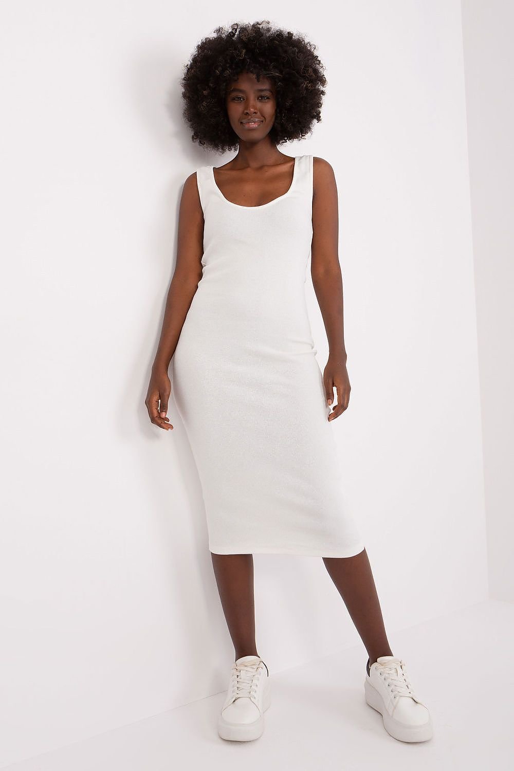 Person wearing a white sleeveless dress against a plain background