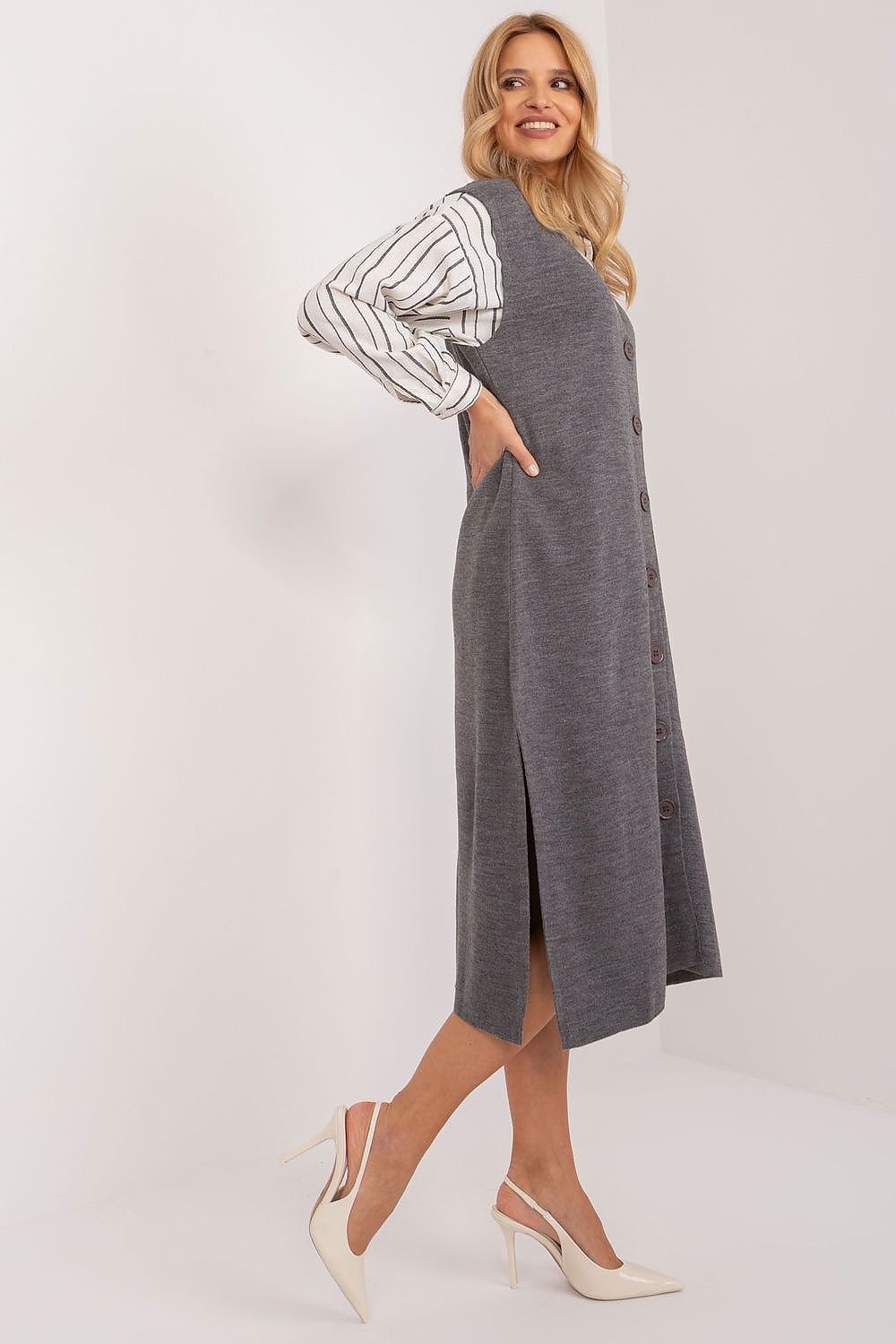 Woman wearing a gray dress over a striped shirt on a white background