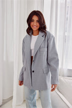 Woman wearing a gray coat in a bright room with white curtains