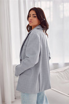 Woman wearing a gray blazer in a bright room