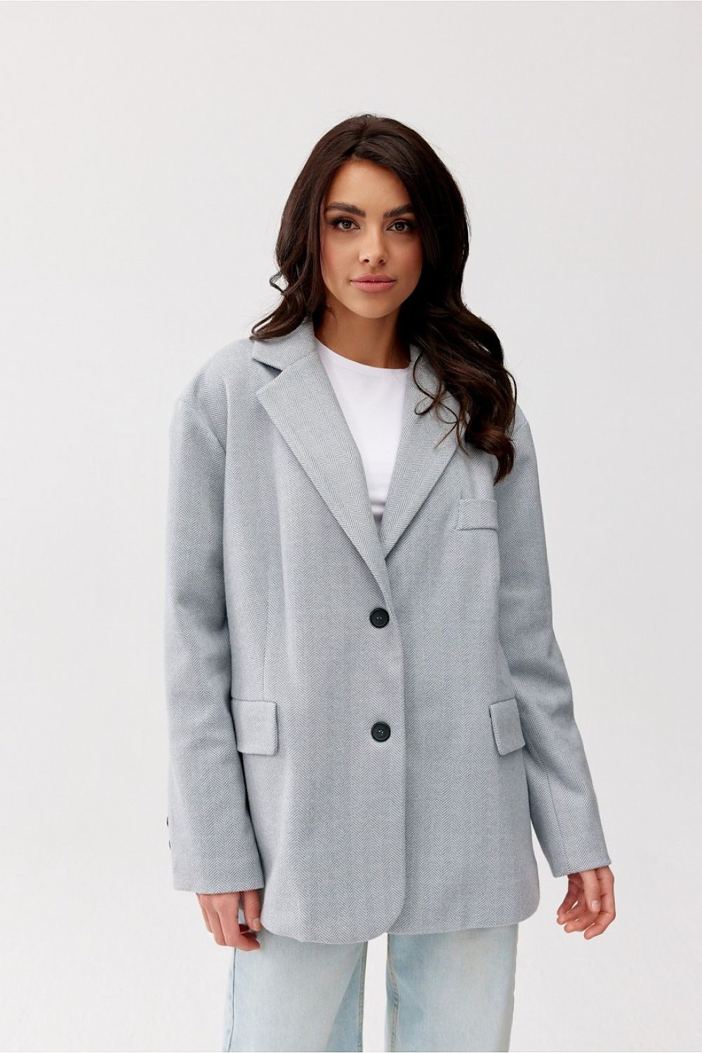 Woman wearing a gray blazer over a white top on a light gray background