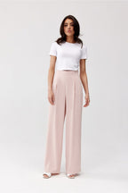 Woman wearing a white t-shirt and light pink wide-leg pants on a white background