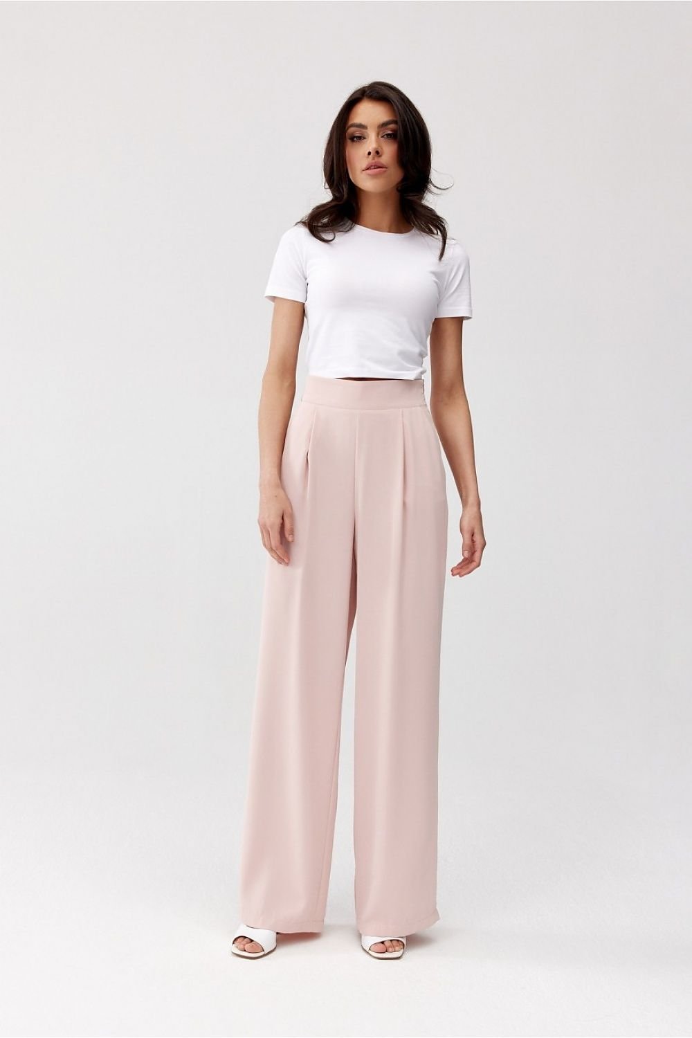 Woman wearing a white t-shirt and light pink wide-leg pants on a white background
