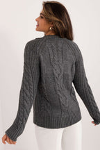 Woman wearing a gray cable knit sweater on a white background