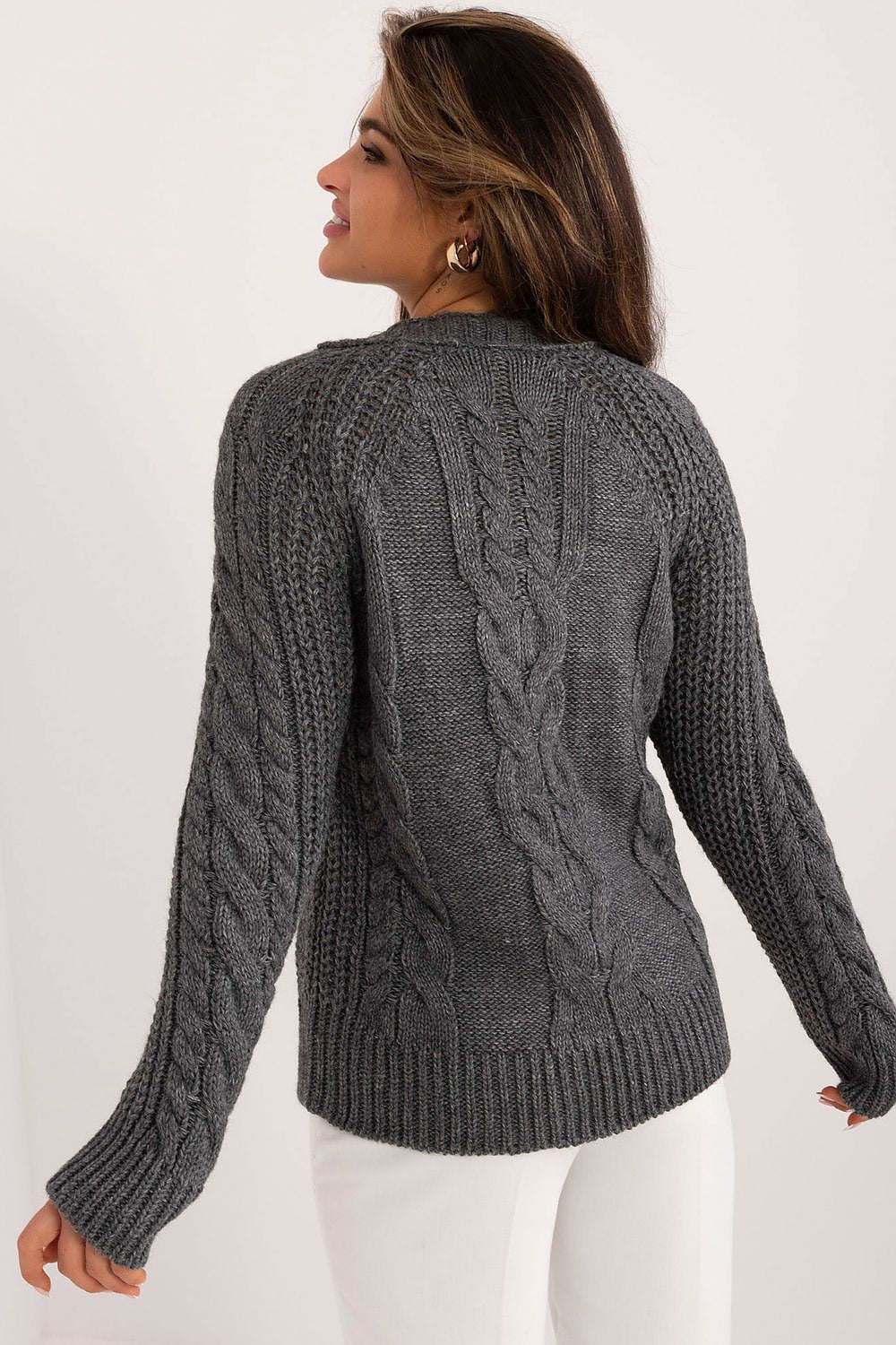 Woman wearing a gray cable knit sweater on a white background