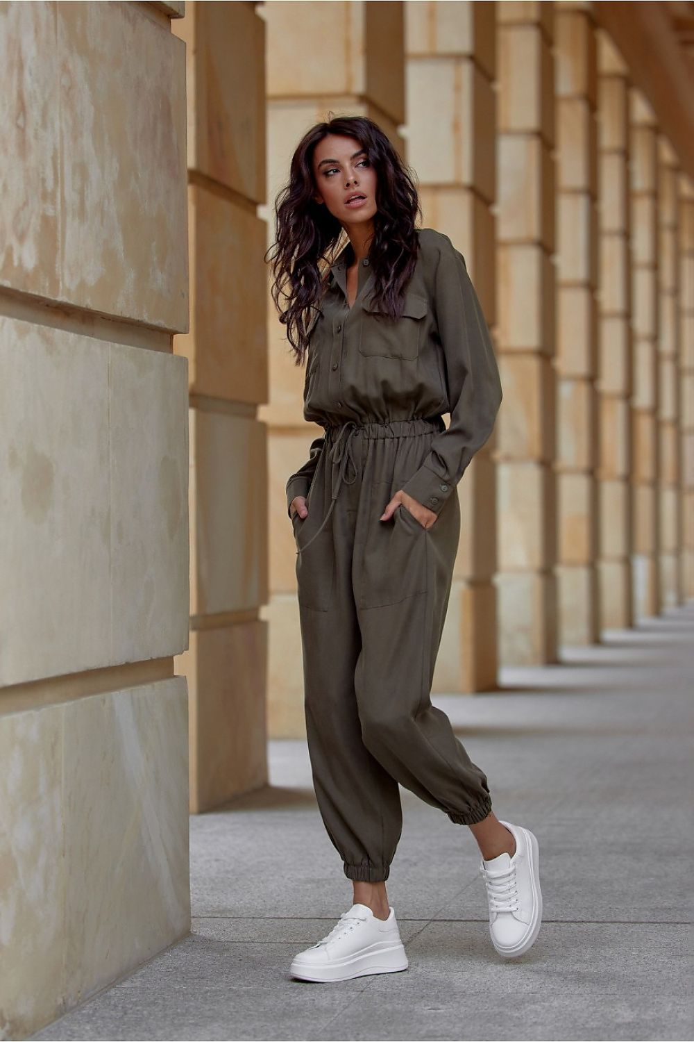 Woman in a green outfit standing in an architectural setting
